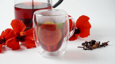 Şeffaf bir bardak ve sıcak kırmızı çiçek çayı.