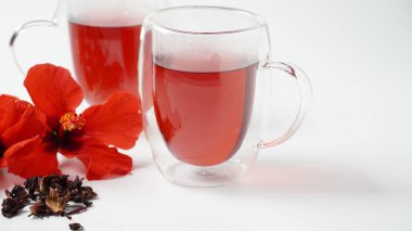 Şeffaf bir bardak ve sıcak kırmızı çiçek çayı.