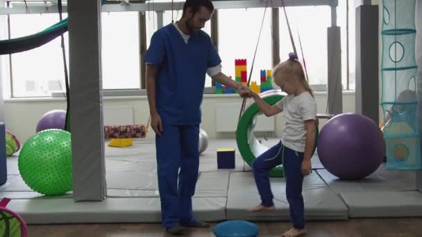 Niña con terapeuta hacer ejercicio en la almohadilla táctil masajeador de pies durante la sesión de integración sensorial. Trastorno del procesamiento sensorial — Vídeos de Stock