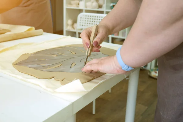 Femme potier main faisant feuille de monstère d'argile en atelier de poterie studio. Processus de création de vase en céramique. Fabriqué à la main, art de passe-temps et concept d'artisanat — Photo