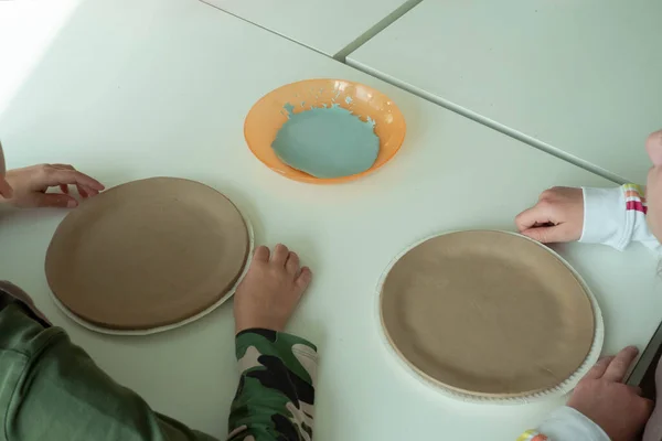 Pintura infantil com esponja em placa de cerâmica de barro em estúdio oficina de cerâmica. Desenvolvimento da arte e pintura em crianças. Close-up — Fotografia de Stock