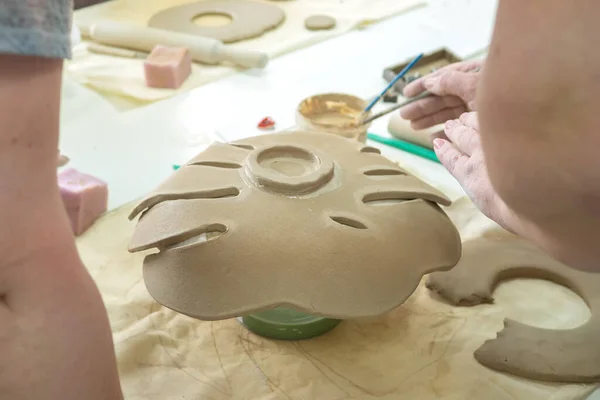 陶芸工房で粘土のモンスターの葉を作る女性の手の陶芸家。セラミック花瓶を作成するプロセス。手作り、趣味芸術、手芸のコンセプト — ストック写真