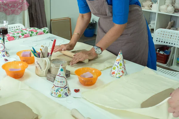 Vrouwelijke keramist rolt klei met behulp van houten deegroller in keramische studio. Handen van dichtbij. Het maken van aardewerk — Stockfoto