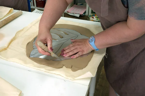 Mujer alfarero de mano haciendo hoja de arcilla monstera en estudio de taller de cerámica. Proceso de creación de jarrón de cerámica. Hecho a mano, arte hobby y concepto de artesanía —  Fotos de Stock