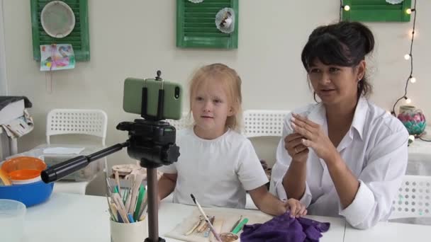 Mulher tutor de cerâmica no estúdio de arte com doughter gravação lição de vídeo para ceramict curso on-line ou leva um master class sobre a criação de produtos cerâmicos. Influenciador criando conteúdo interessante — Vídeo de Stock