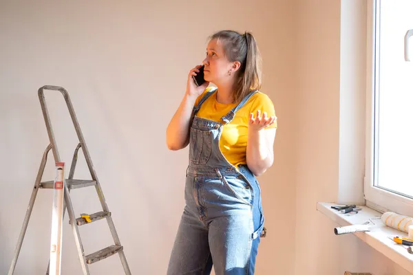 Mujer frustrada cansada haciendo una renovación de la casa y hablar por teléfono. dificultades y problemas de pánico una joven y ella llama a los constructores. — Foto de Stock