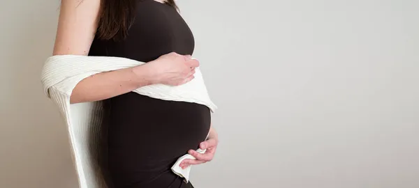 Widok z boku elegancka kobieta w ciąży w sukience z brzuchem w rękach. zdrowa koncepcja ciąży. Baner copyspace dla tekstu — Zdjęcie stockowe