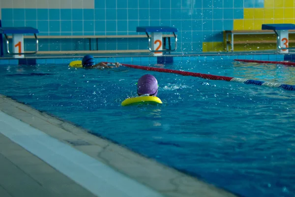 Nierozpoznawalne dziecko pływanie styl freestyle szkolenia w basenie pływak z rozbryzgu wody. — Zdjęcie stockowe