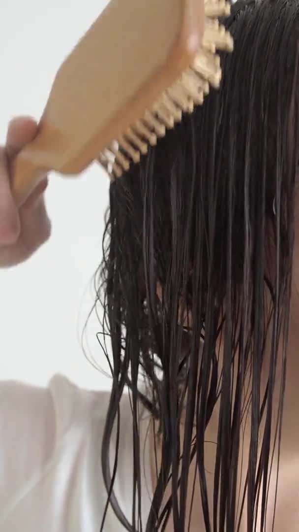 Woman brushing with combs tangled hair with conditioner after shower slow motion. — Stock Video