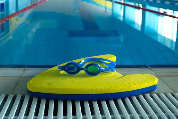 Spor merkezinde yüzme havuzunun yanında gözlüklerle yüzme tahtası. Yüzme eğitimi konsepti. metin için boşluk kopyala. — Stok fotoğraf