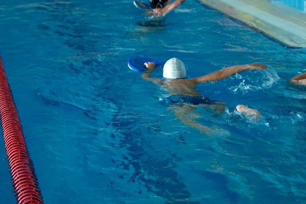 Barn oigenkännlig grupp simning freestyle stil träning i pool med stänk vatten. — Stockfoto