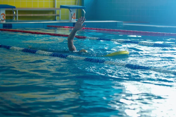 Onherkenbaar kind zwemmen freestyle stijl training in zwemmer zwembad met spetterend water. — Stockfoto