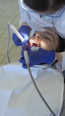 Diş hekimi ultrasonlu hastaya ağız temizliği yapar. Diş kliniğinde plaket ve tartar temizliği..