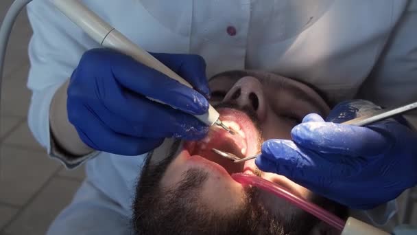 El dentista realiza la higiene bucal al paciente con ultrasonido. Limpieza de placa y sarro en una clínica dental. — Vídeo de stock