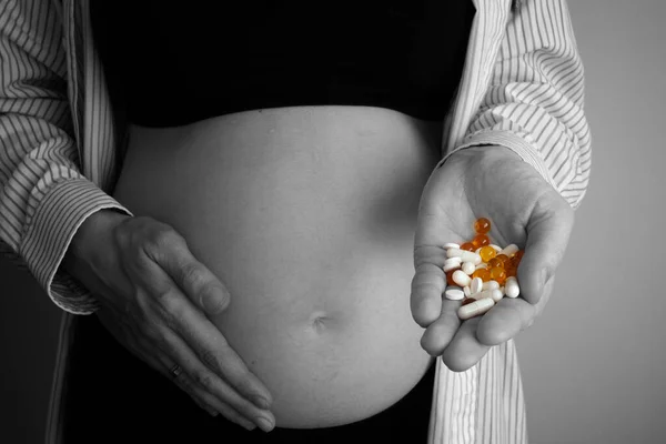 妊娠中の女性は薬を手に持っている。妊娠中に抗うつ薬や薬を服用する概念.白黒写真. — ストック写真