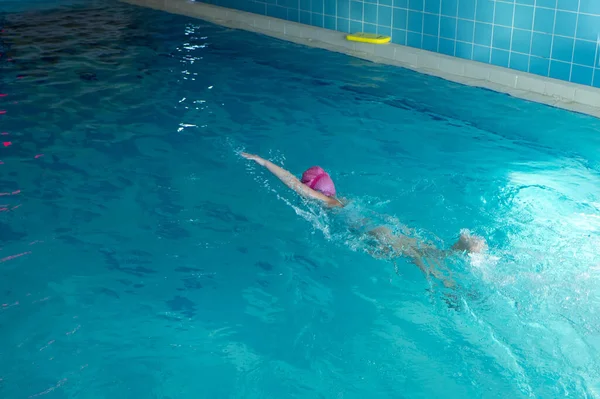 Criança irreconhecível natação estilo freestyle treinamento na piscina nadador com salpicos de água. — Fotografia de Stock