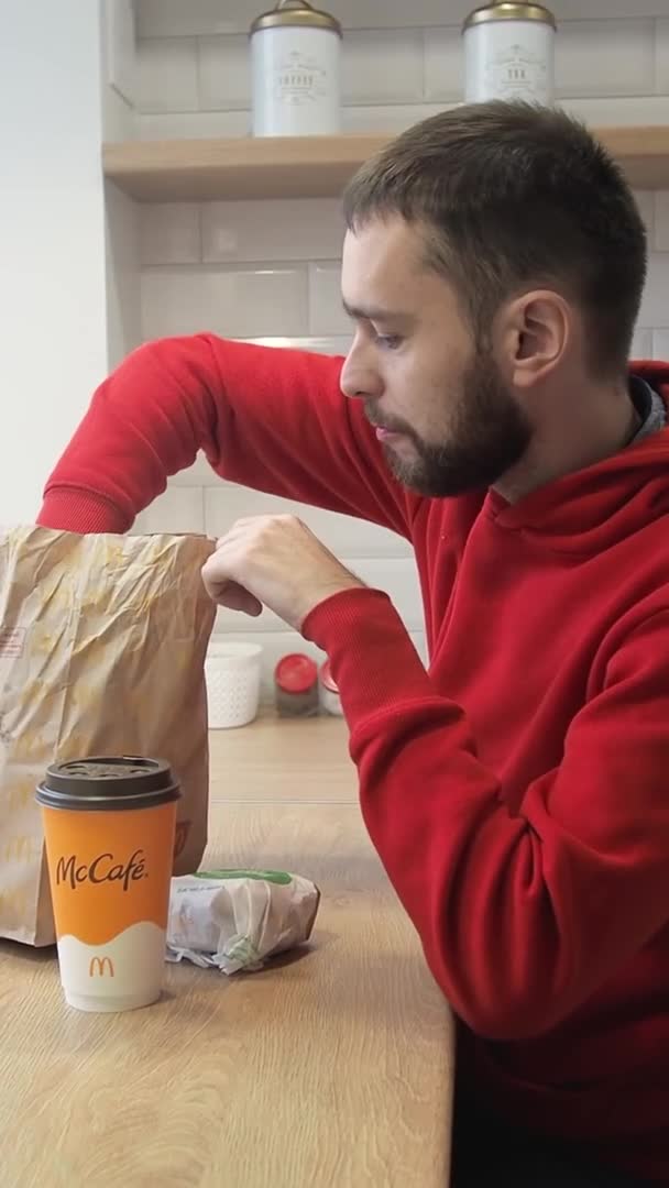 若い男は自宅でおいしいテイクアウト食品マクドナルドを食べる。隔離孤独と隔離中の食品配達の概念.Minsk, BELARUS - 2021年10月1日 — ストック動画