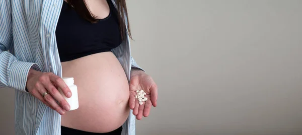 Donna incinta irriconoscibile che tiene delle pillole sulla mano. Concetto di vitamine per la salute in gravidanza — Foto Stock