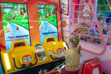 Minsk, BELARUS - 14 Eylül 2021: Küçük kız çocuk alışveriş merkezinde konsol oyunu oynuyor.