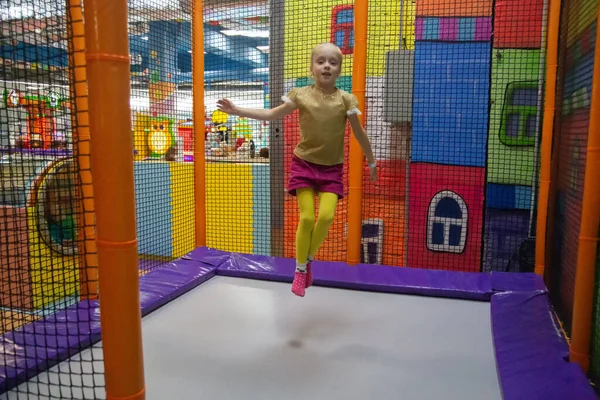 Niño pequeño saltando en el trampolín en el patio interior. Niña activa divirtiéndose en el centro deportivo — Foto de Stock