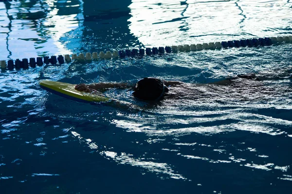 Onherkenbaar kind zwemmen freestyle stijl training in zwemmer zwembad met spetterend water. — Stockfoto