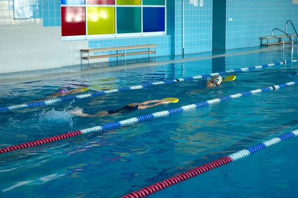 Treino de natação na piscina. Adolescentes e caras aprendem a nadar em estilo livre com pranchas de banho — Fotografia de Stock