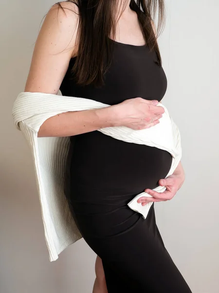 サイドビューのエレガントな妊婦の手の中に腹をドレスアップ。健康的な妊娠の概念。垂直. — ストック写真