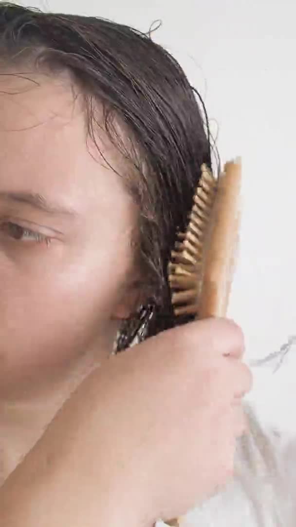 Женщина расчесывает расчески запутанными волосами с кондиционером после душа замедленной съемки. — стоковое видео