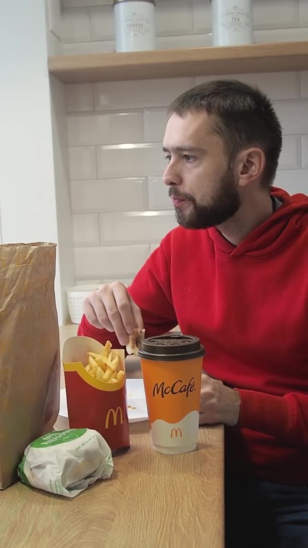 Jongeman die heerlijk afhaalvoedsel eet McDonalds thuis. Het concept van voedsellevering tijdens quarantaine eenzaamheid en isolatie. Minsk, BELARUS - 1 oktober 2021 — Stockvideo