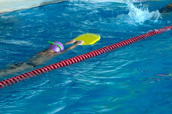 难以辨认的孩子在有泼水的游泳池里自由泳风格的训练. — 图库照片
