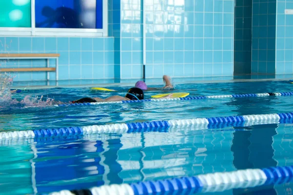 Enfants groupe de natation style freestyle formation dans la piscine avec éclaboussures d'eau. — Photo