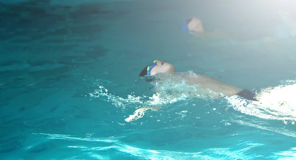 Kid zwemmen freestyle stijl training op terug in het zwembad met spetterend water. selectieve focus. — Stockfoto