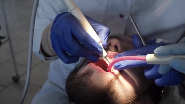 Der Zahnarzt führt die Mundhygiene des Patienten mit Ultraschall durch. Zahnbelag und Zahnstein in einer Zahnklinik reinigen. — Stockvideo
