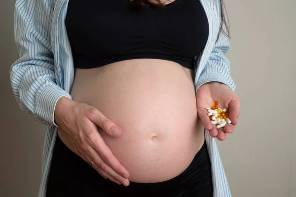 Donna incinta irriconoscibile che tiene delle pillole sulla mano. Concetto di vitamine per la salute in gravidanza — Foto Stock