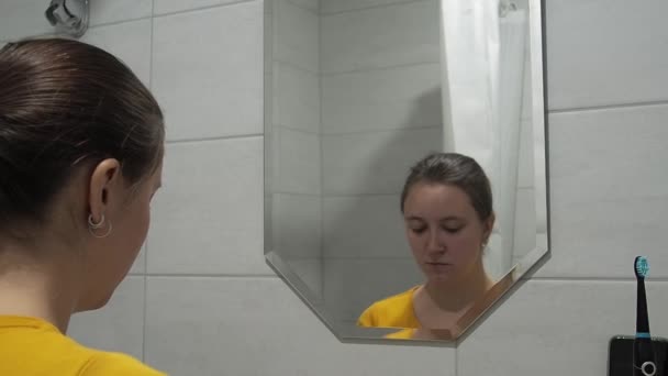 Młoda kobieta używa pianki do mycia twarzy w łazience. Pojęcie codziennej pielęgnacji skóry i samoopieki w każdym wieku. — Wideo stockowe