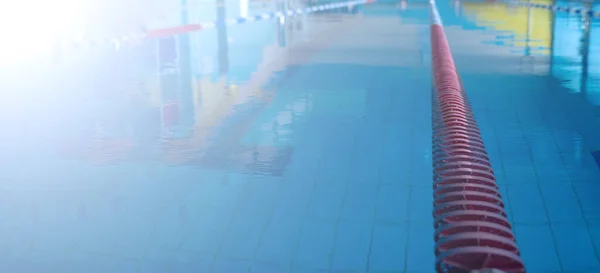 Blue pool water and red swimming lane marker in swimming pool with flare. banner blurred pattern with copy space for text . — Stock Fotó