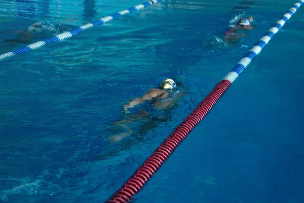 Дитина плаває вільним стилем тренування в плавальному басейні з бризкою води . — стокове фото
