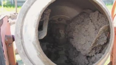 İnşaat alanında taşınabilir beton karıştırıcı. Odaklanırken mikserin yakın çekimini yap ve inşaat için taze beton yap. yavaş çekim.