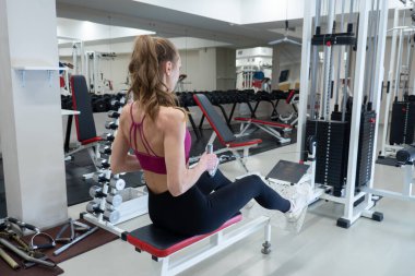 Spor salonunda kürek çekme makinesinde egzersiz yapan kendine güvenen genç bir sporcu. Sağlıklı spor eğitimi kavramı