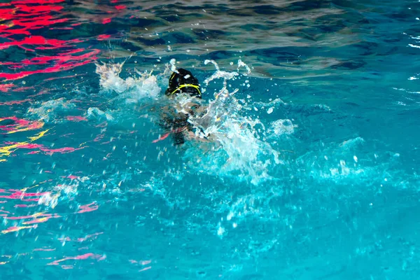 Irriconoscibile bambino nuoto stile freestyle formazione in piscina nuotatore con spruzzi d'acqua. — Foto Stock