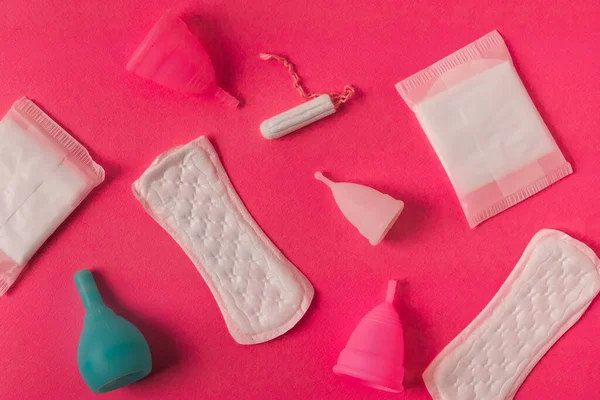 Diferentes tipos de produtos de materiais de higiene menstrual femininos, como absorventes tampões e copos. Fundo rosa. Fotografia De Stock