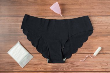 Farklı türde kadınsı adet hijyen ürünleri, pedler, pedler, tamponlar ve iç çamaşırlı bardaklar. tahta arkaplan.