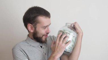 Büyük cam kavanozu elinde tutan ve onu okşayan bir adam. Para biriktirme konsepti. ılımlı tüketim ve ekonomi.