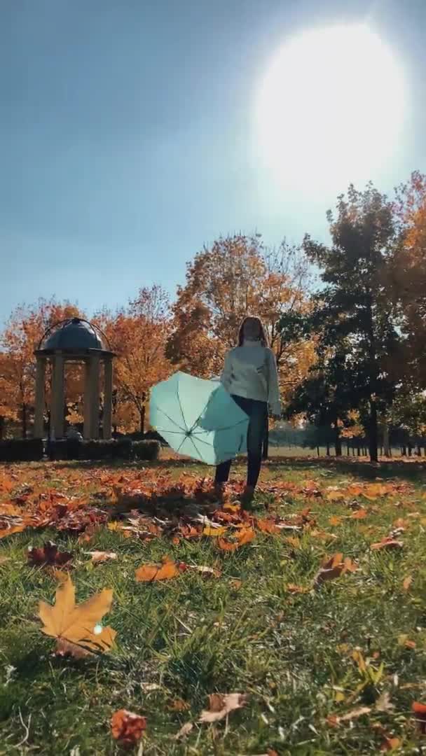 Happy woman throwing autumn colorful leaves from under umbrella — Stock Video