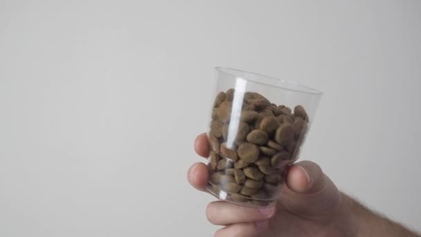 Homem segurando comida de cão em um copo de medição para medir o volume da porção diária de alimentos. Restrições de saúde animal de estimação ou dieta . — Vídeo de Stock