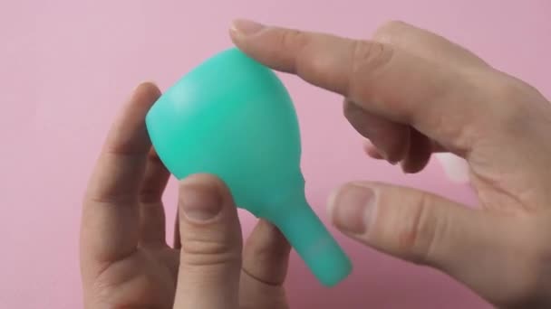 Mulher mão segurando diferentes tipos de copos menstruais e demonstrando dobra C métodos de dobramento — Vídeo de Stock