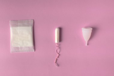 Kadınsı adet hijyen ürünlerinin farklı türleri. Pedler, pedler, tamponlar ve fincanlar gibi. Pembe arkaplan.