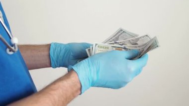 Erkek tıp doktoru el ele tutuşup onları sayarak yüz dolarlık banknotları tutuyor. Sağlık hizmetlerinde yolsuzluk kavramı. Doktora rüşvet ver..