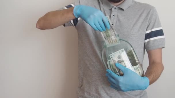 Homem segurando grande frasco de vidro e dá dinheiro de um depósito e uma reserva para pagar dívidas — Vídeo de Stock