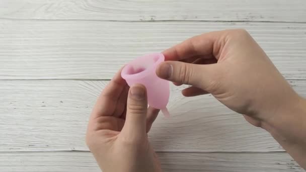 Mulher mão segurando copo menstrual e demonstrando labia métodos de dobramento — Vídeo de Stock